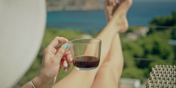 woman holding a drink with legs propped up overlooking body of water